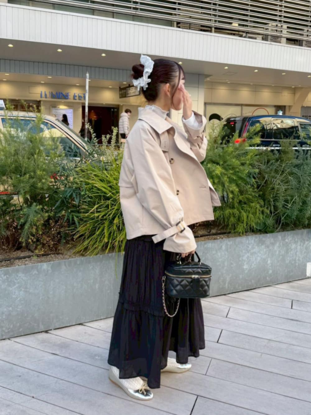 ベージュ系のトレンチコート、ホワイト系のTシャツ/カットソー、ブラック系のワンピースを着用したレディースの冬コーディネートの2枚目の写真