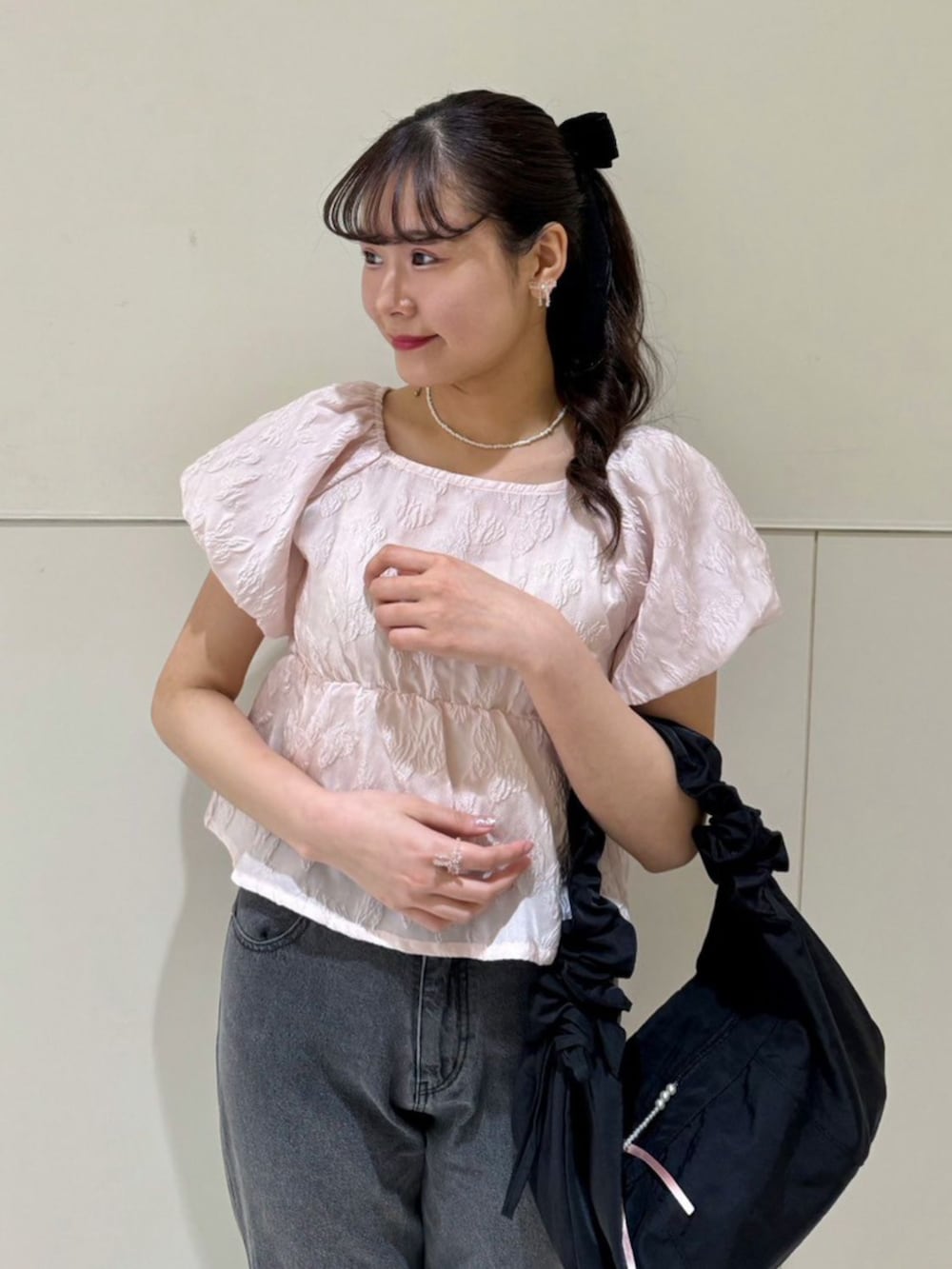 ブラック系のデニムパンツ、ブラック系のショルダーバッグ、ピンク系のシャツ/ブラウスを着用したレディースの春コーディネートの2枚目の写真