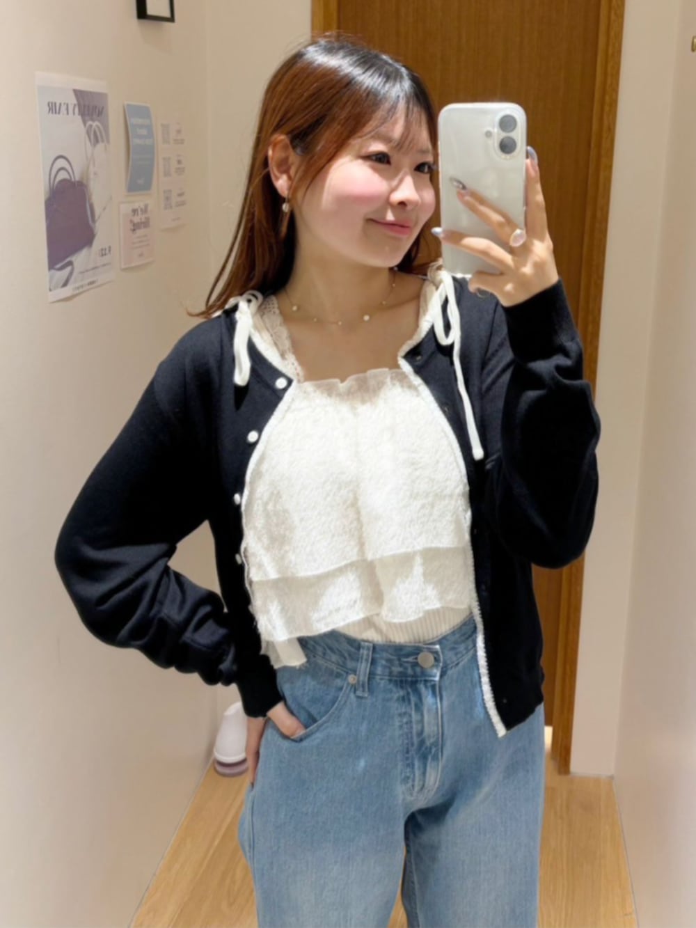 ブルー系のデニムパンツ、ホワイト系のキャミソール、ブラック系のカーディガン/ボレロを着用したレディースの秋コーディネートの2枚目の写真