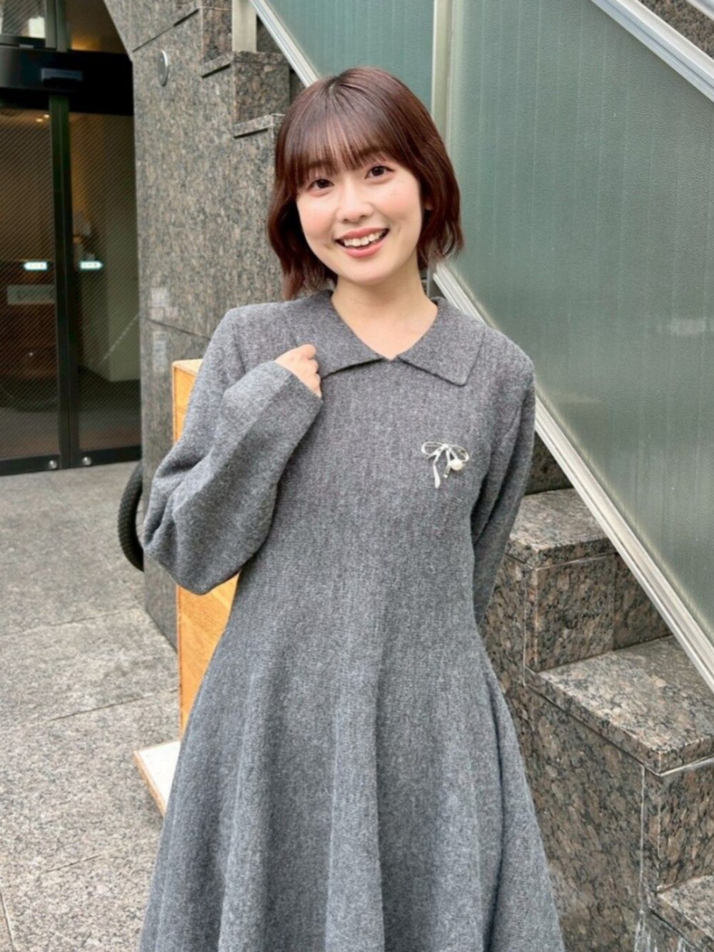グレー系のワンピース/ドレス、ブラウン系のブーツ、シルバー系のブローチ/コサージュを着用したレディースの秋コーディネートの2枚目の写真