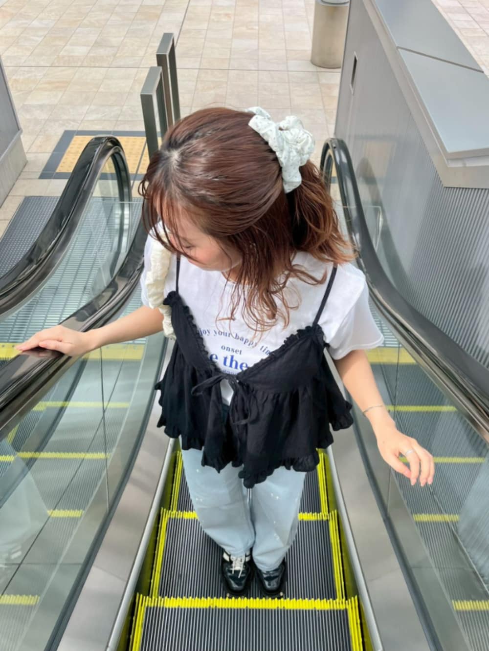 ホワイト系のショルダーバッグ、ブルー系のデニムパンツ、ブラック系のキャミソールを着用したレディースの夏コーディネートの3枚目の写真