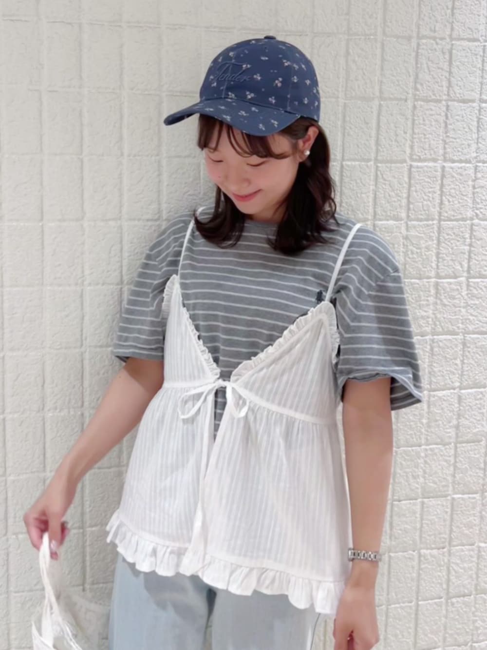ブルー系のデニムパンツ、ホワイト系のキャミソール、ブルー系のキャップを着用したレディースの夏コーディネートの3枚目の写真