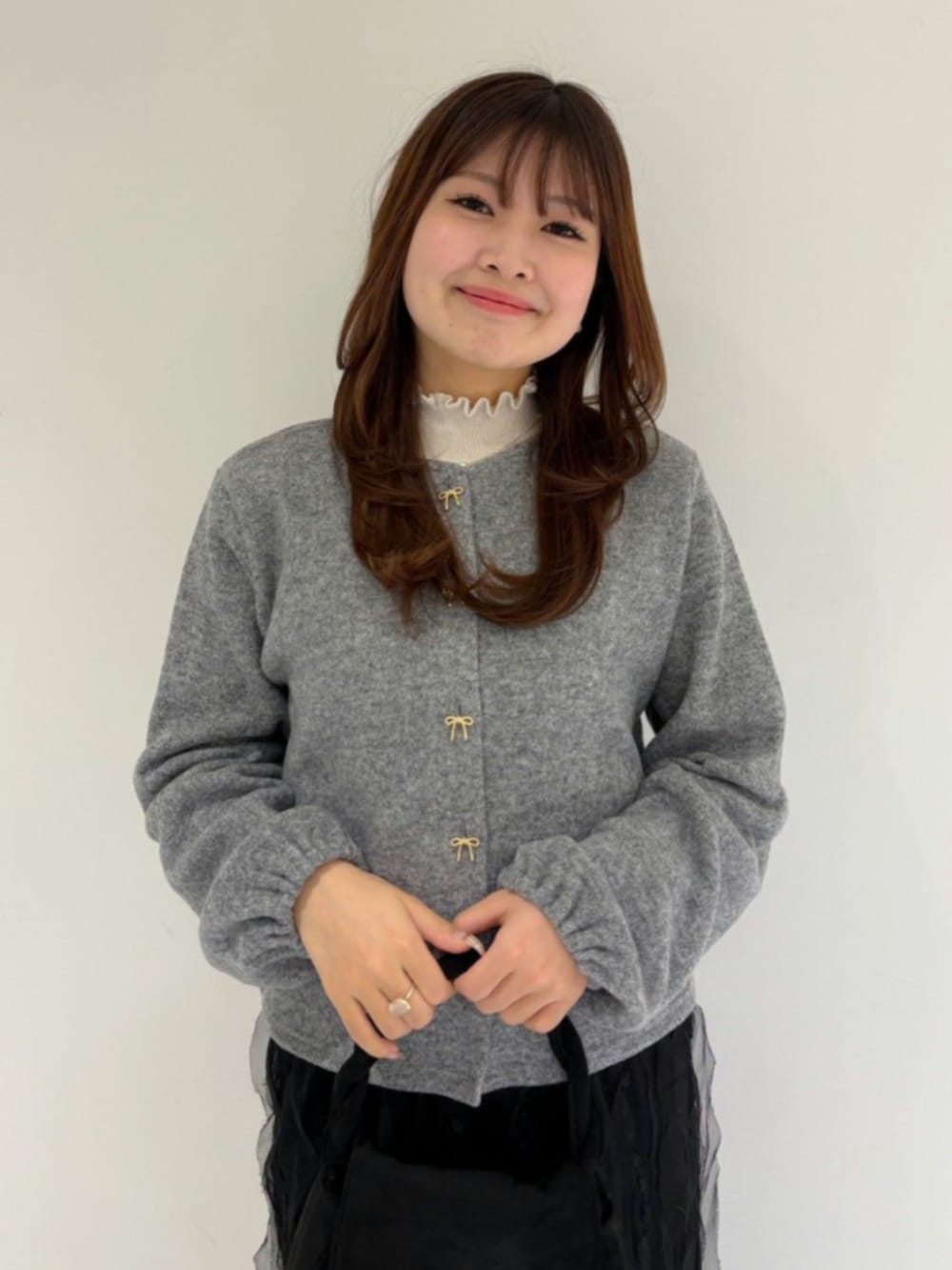 ブラック系のショルダーバッグ、ホワイト系のニット/セーター、グレー系のカーディガン/ボレロを着用したレディースの秋コーディネートの2枚目の写真