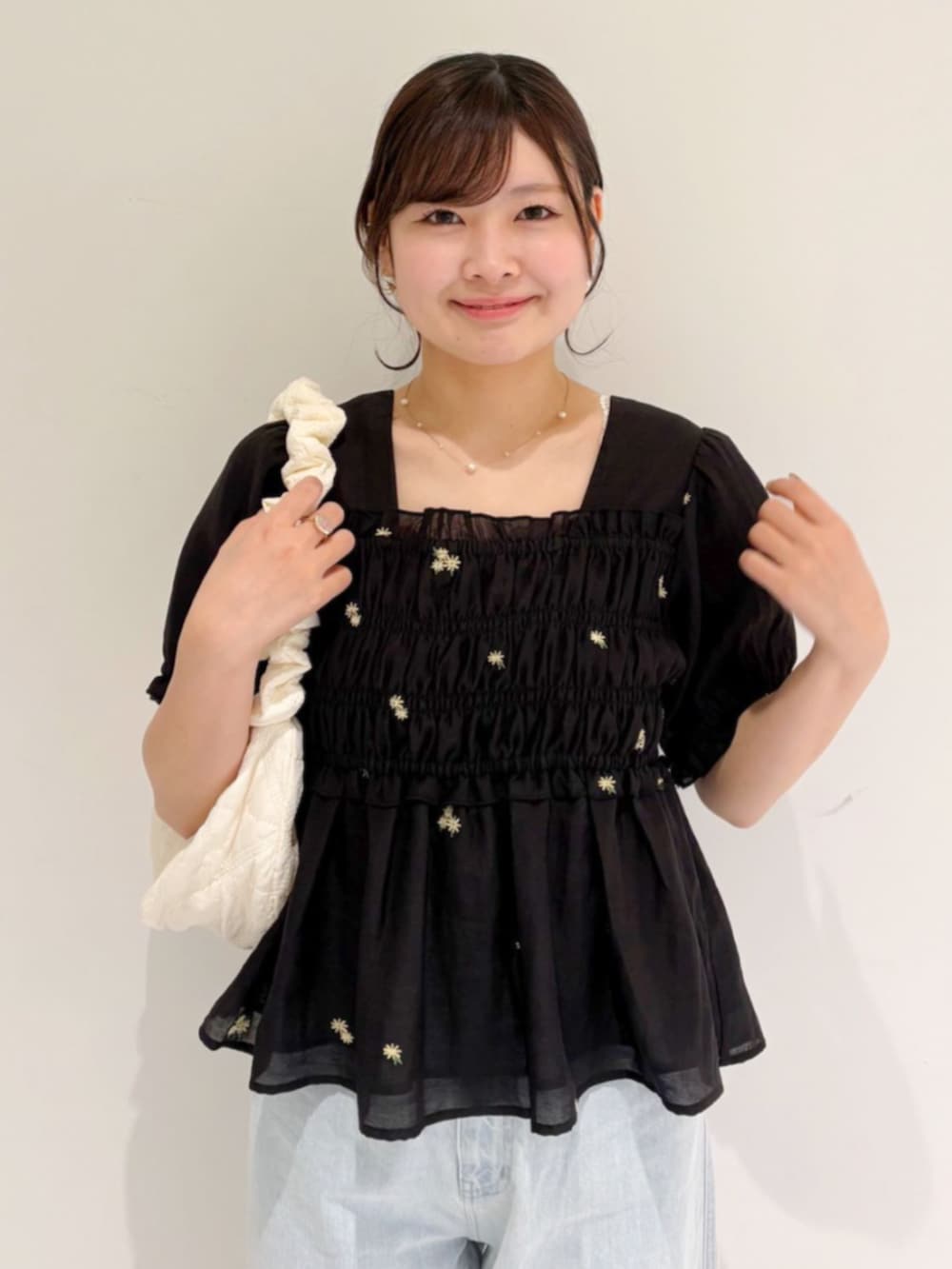 ホワイト系のショルダーバッグ、ブルー系のデニムパンツ、ブラック系のシャツ/ブラウスを着用したレディースの春コーディネートの2枚目の写真