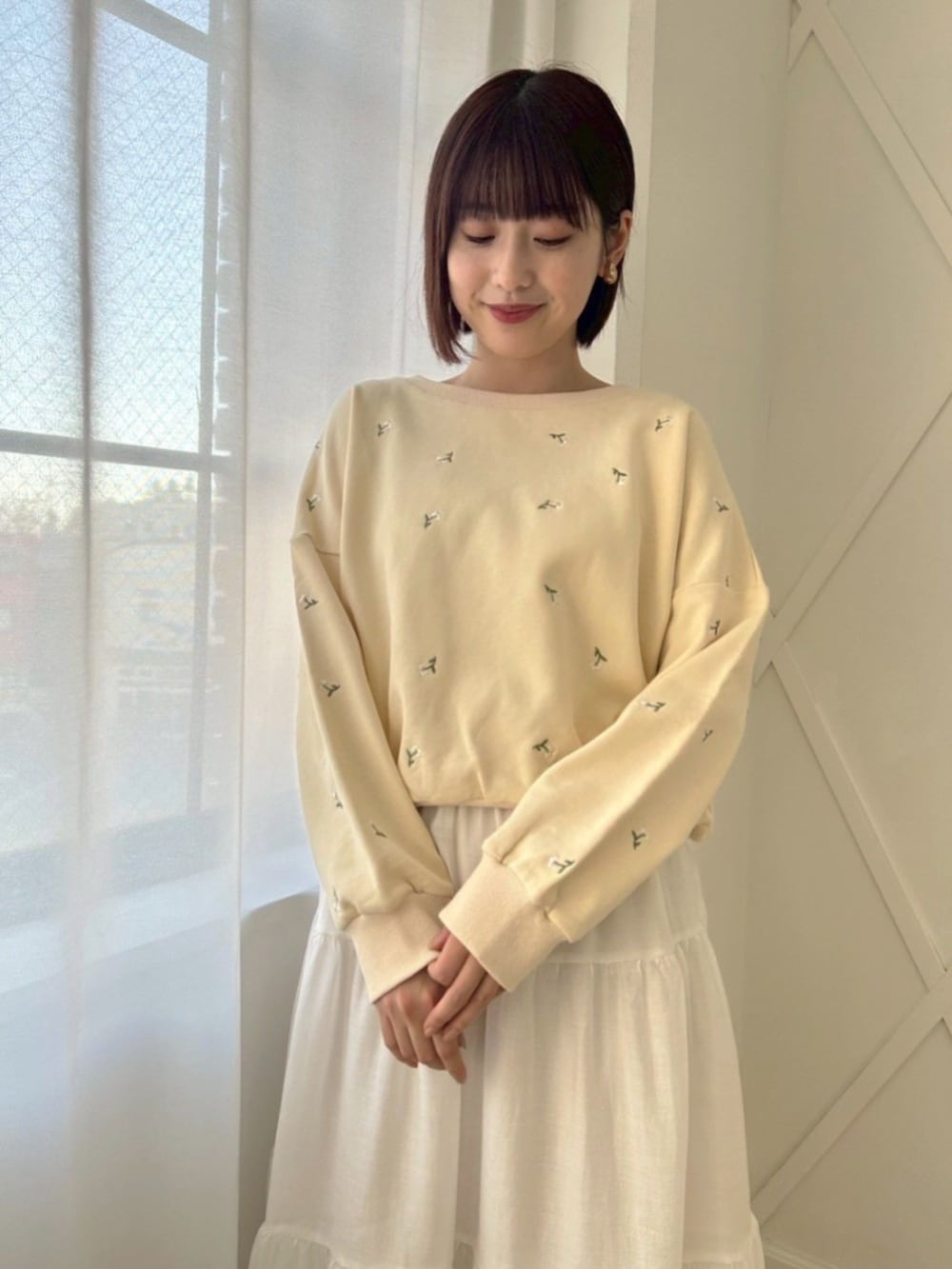 ホワイト系のスカート、イエロー系のスウェット、ゴールド系のバレエシューズを着用したレディースの冬コーディネートの2枚目の写真