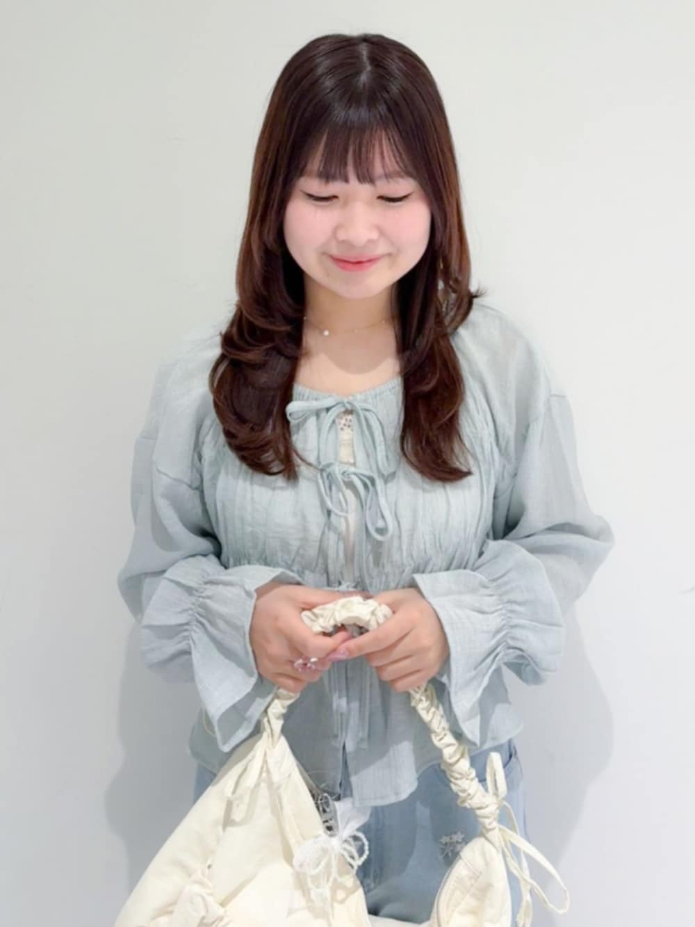 ホワイト系のショルダーバッグ、グレー系のシャツ/ブラウス、ブルー系のデニムパンツを着用したレディースの春コーディネートの2枚目の写真