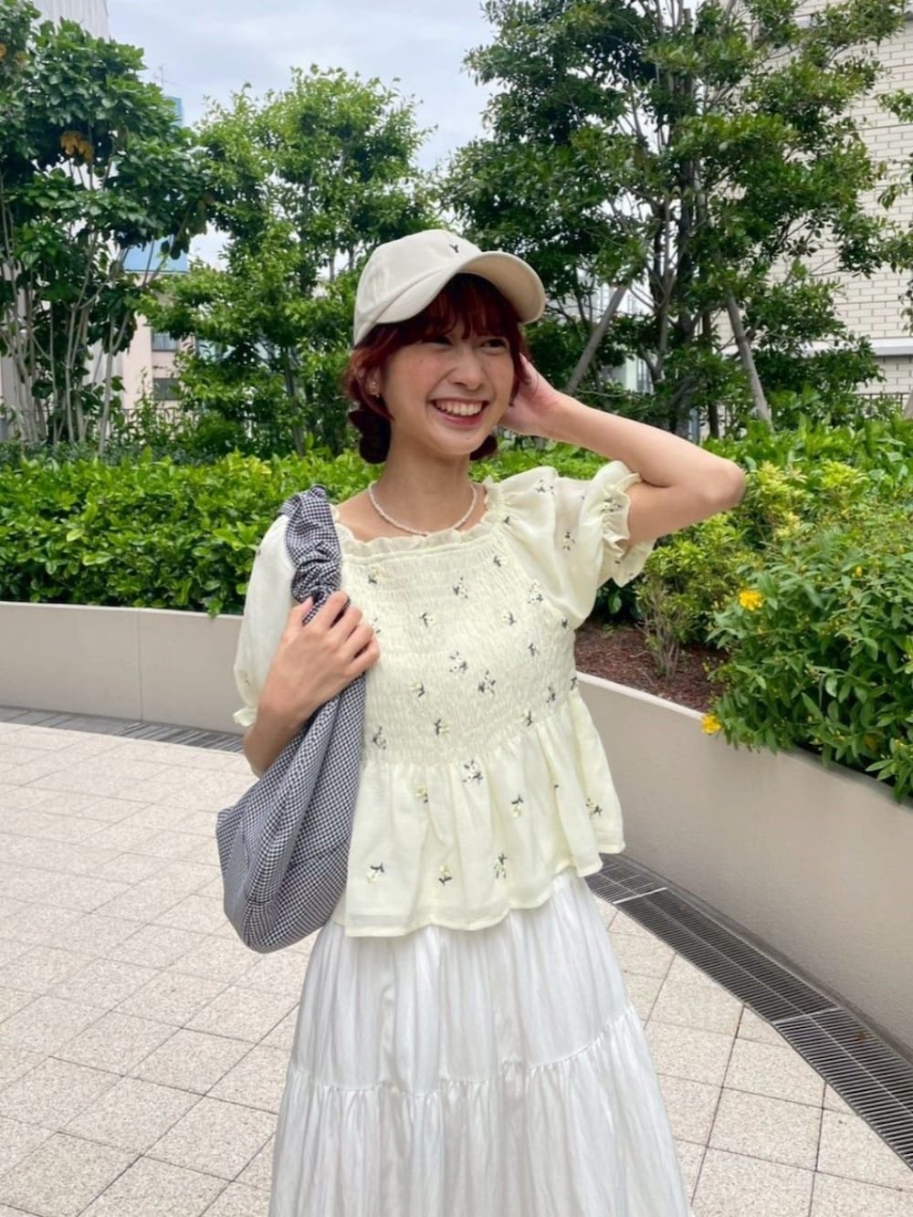 ブラック系のショルダーバッグ、ホワイト系のスカート、イエロー系のシャツ/ブラウスを着用したレディースの夏コーディネートの2枚目の写真