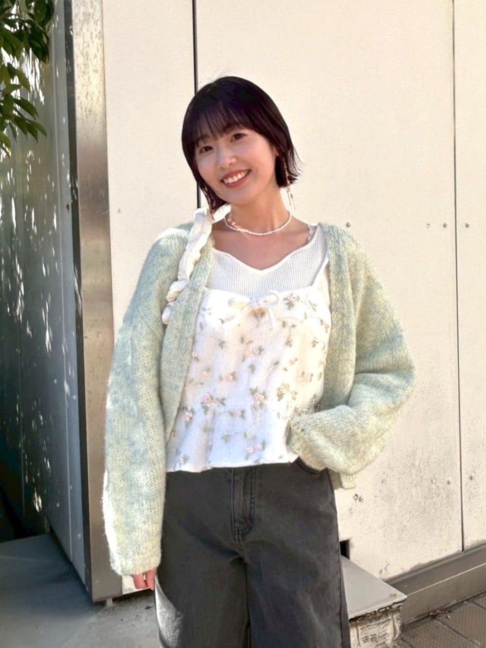 ホワイト系のニット/セーター、ホワイト系のキャミソール、ブラック系のデニムパンツを着用したレディースの春コーディネートの2枚目の写真