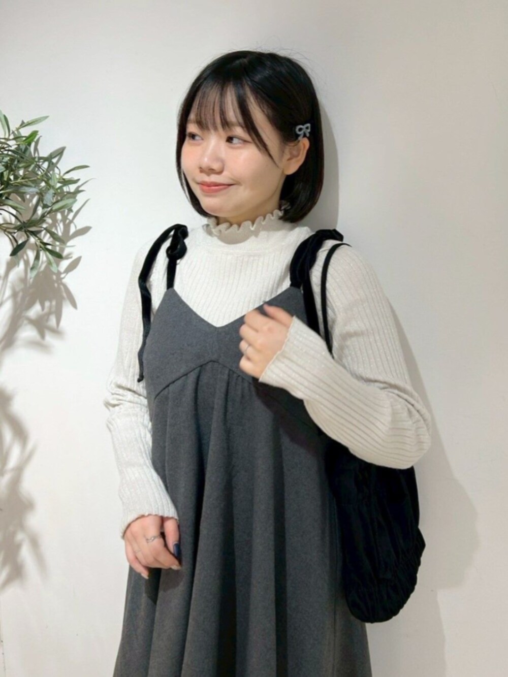 ホワイト系のニット/セーター、ブラック系のショルダーバッグ、グレー系のワンピースを着用したレディースの冬コーディネートの2枚目の写真