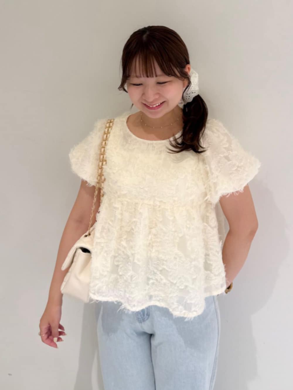 ブルー系のデニムパンツ、ホワイト系のシャツ/ブラウス、ホワイト系のショルダーバッグを着用したレディースの夏コーディネートの2枚目の写真