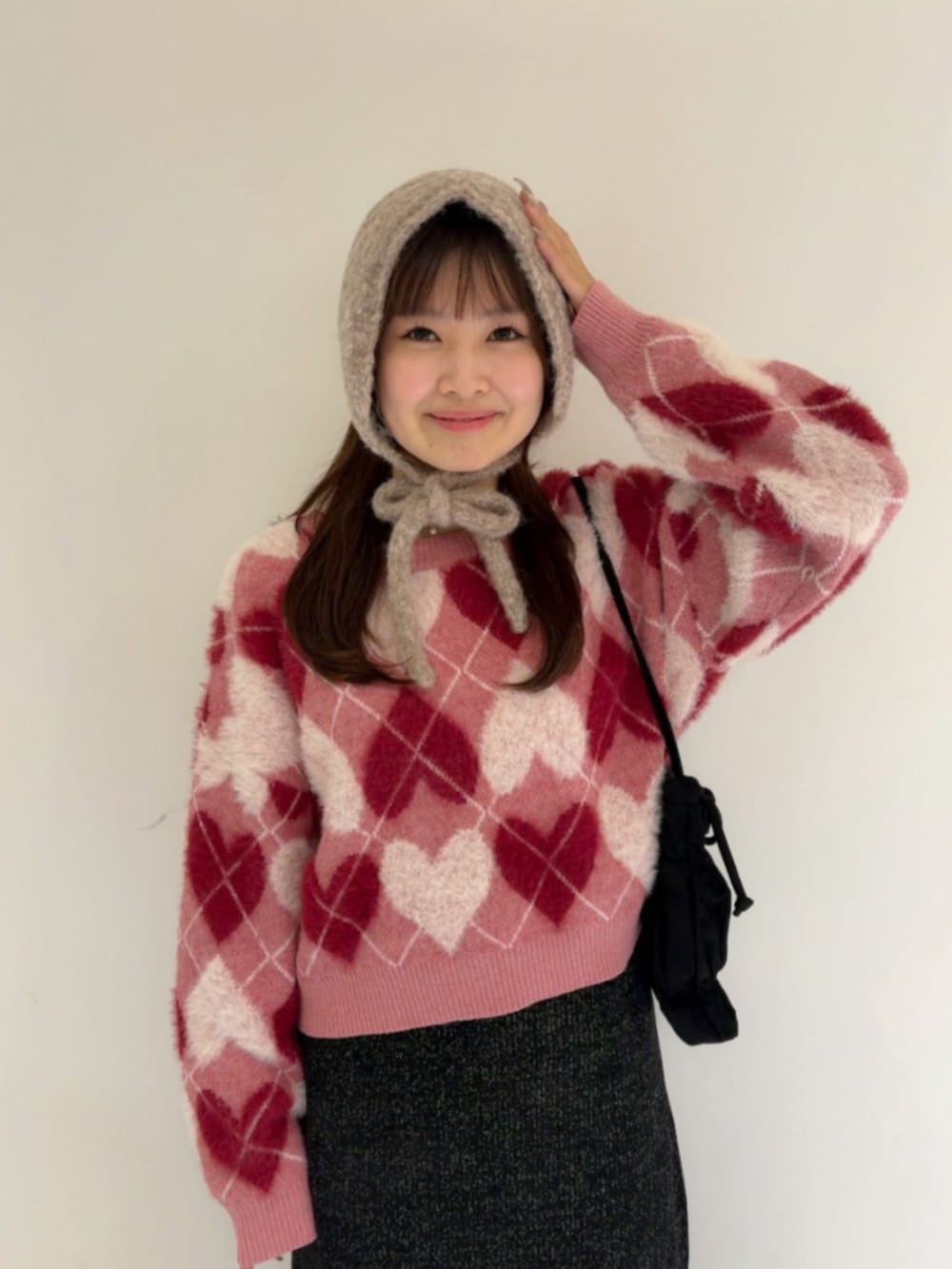 ブラック系のスカート、レッド系のニット/セーター、ブラック系のショルダーバッグを着用したレディースの秋コーディネートの2枚目の写真