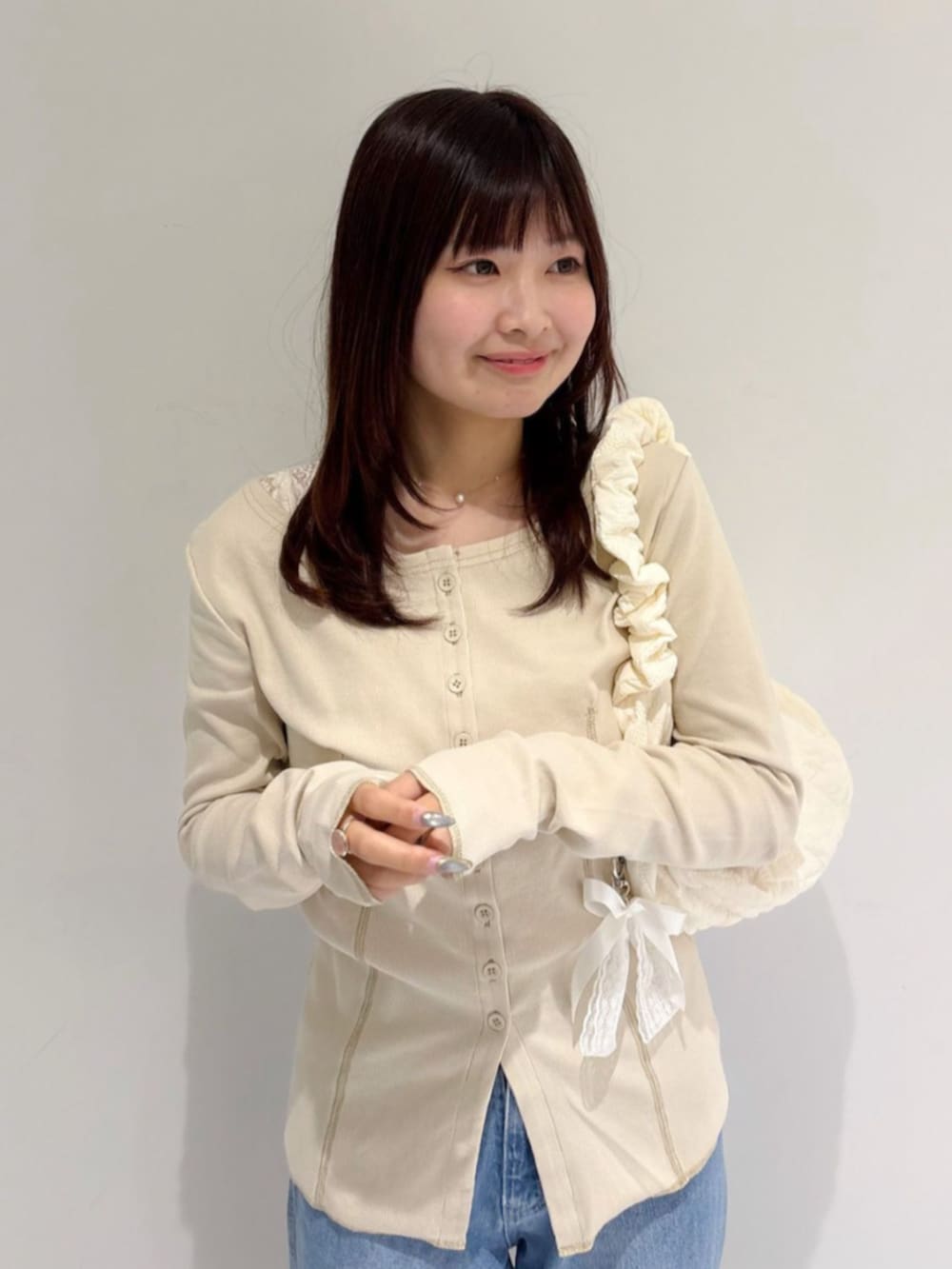 ブルー系のデニムパンツ、ホワイト系のショルダーバッグ、ホワイト系のカーディガン/ボレロを着用したレディースの秋コーディネートの2枚目の写真