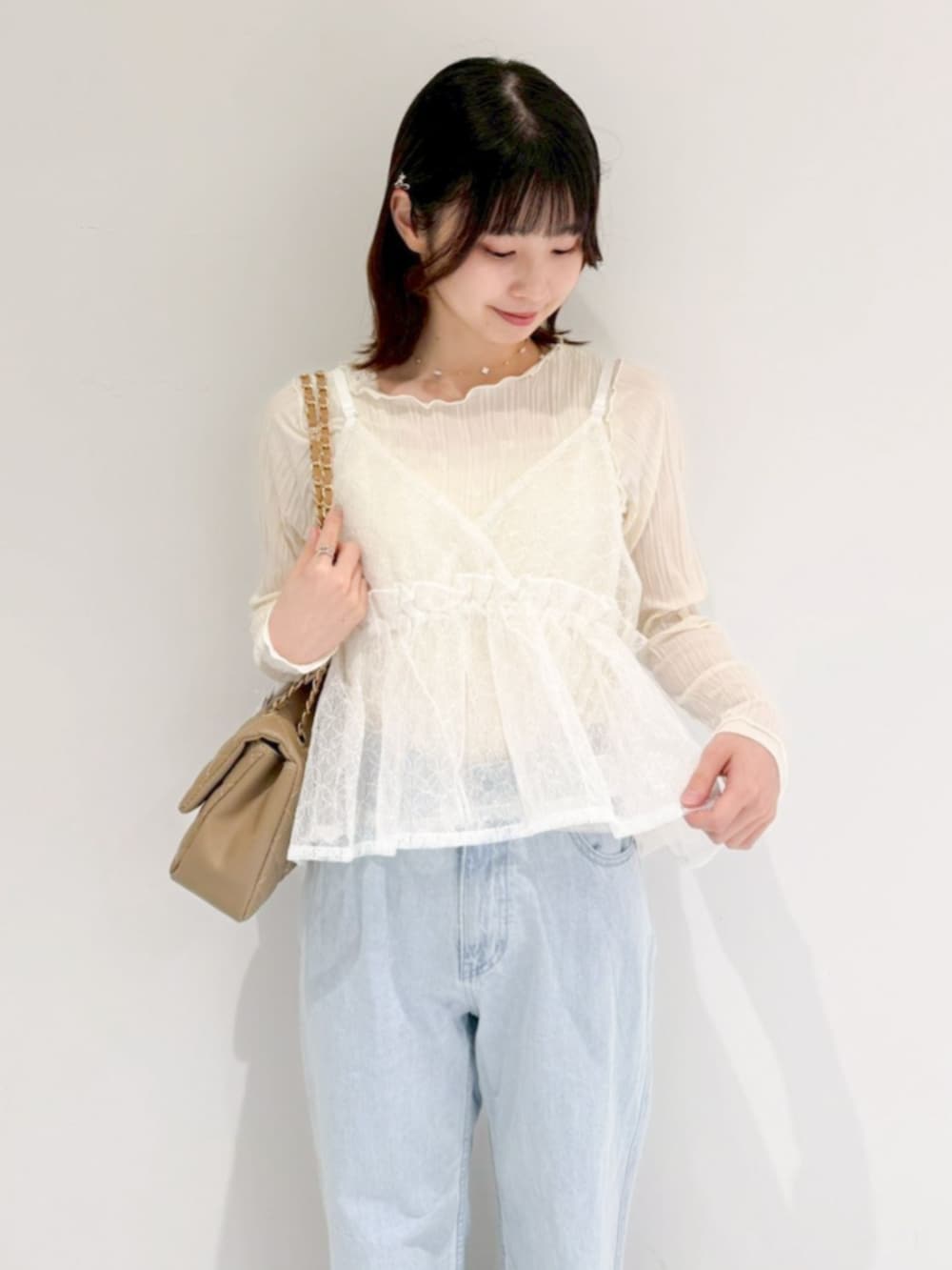 ホワイト系のTシャツ/カットソー、ブルー系のデニムパンツ、ベージュ系のショルダーバッグを着用したレディースの春コーディネートの2枚目の写真