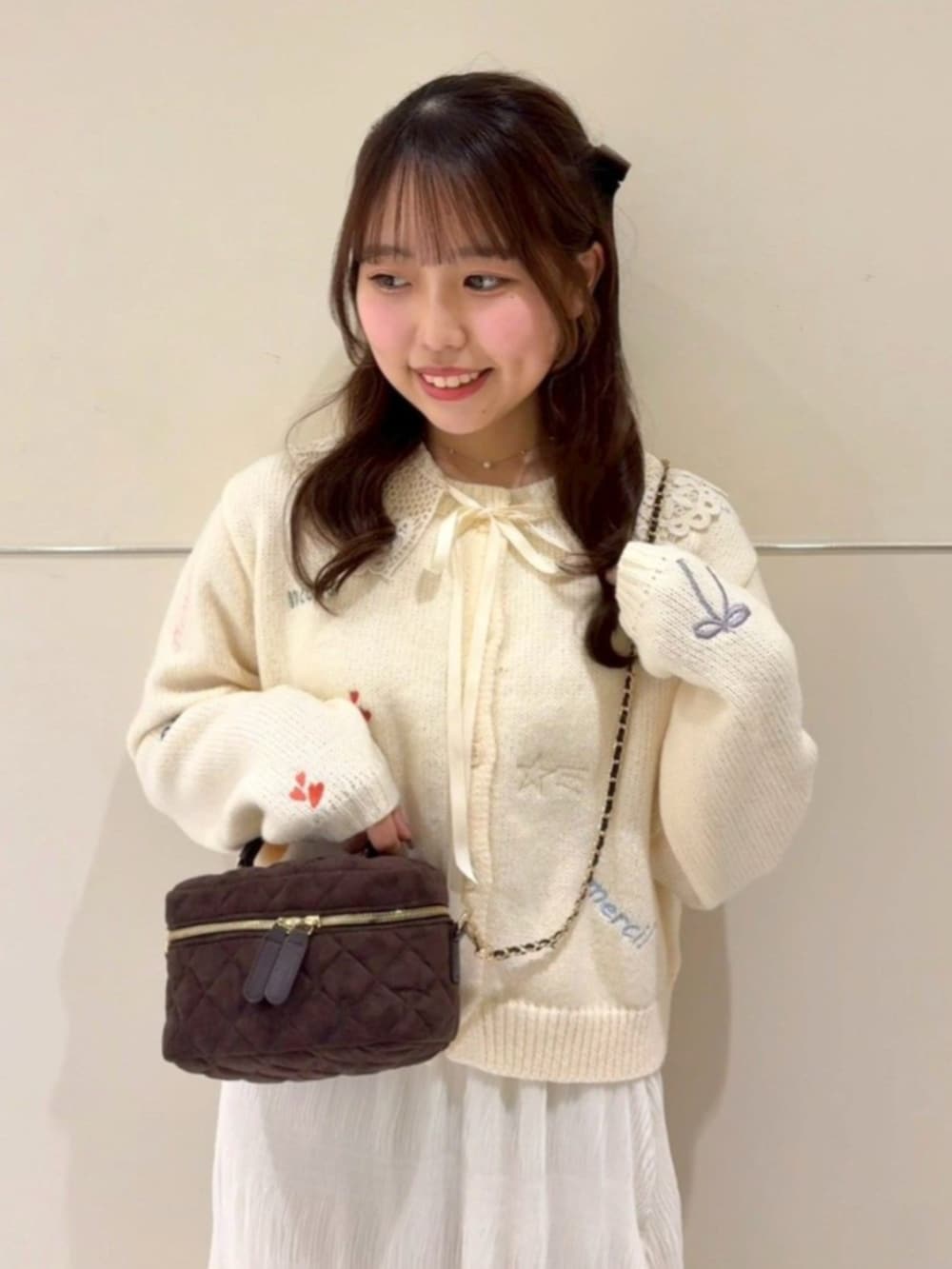 ブラウン系のショルダーバッグ、ホワイト系のスカート、ホワイト系のカーディガン/ボレロを着用したレディースの冬コーディネートの2枚目の写真