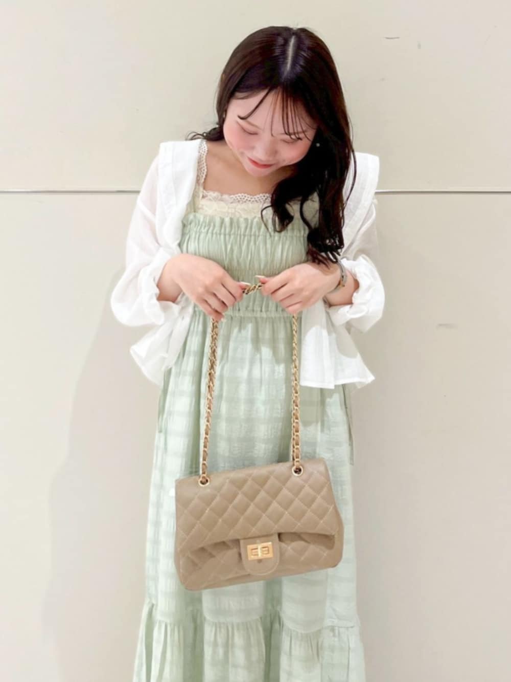 グリーン系のワンピース、ホワイト系のシャツ/ブラウス、ベージュ系のショルダーバッグを着用したレディースの春コーディネートの2枚目の写真