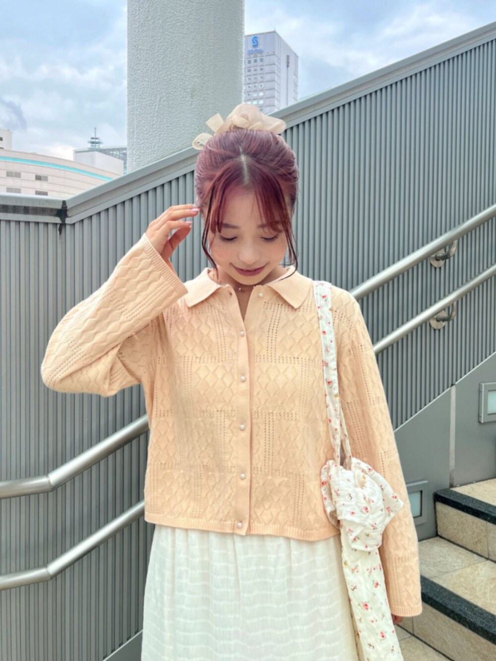 ホワイト系のトートバッグ、オレンジ系のニット/セーター、ホワイト系のスカートを着用したレディースの夏コーディネートの2枚目の写真