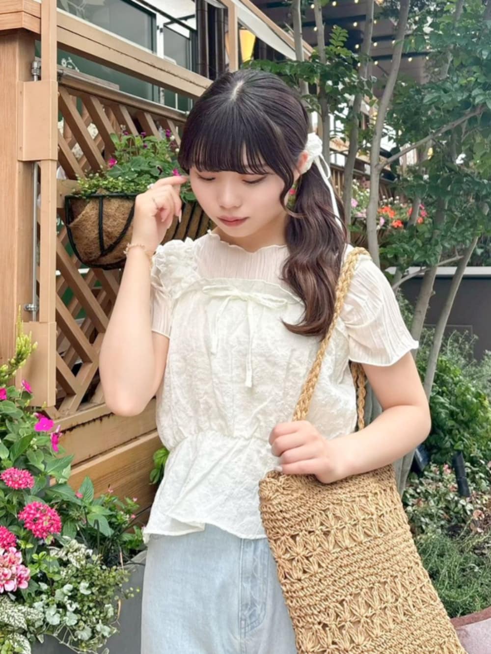 ベージュ系のかごバッグ、ホワイト系のTシャツ/カットソー、ブルー系のデニムパンツを着用したレディースの夏コーディネートの2枚目の写真