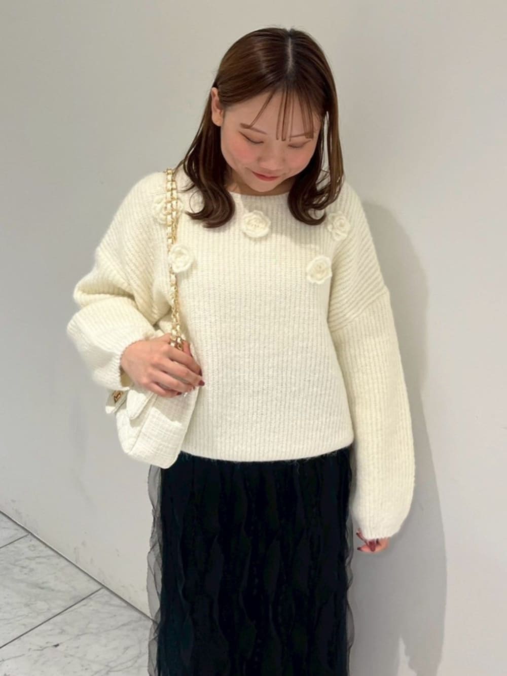 ホワイト系のショルダーバッグ、ブラック系のスカート、ホワイト系のムートンコートを着用したレディースの秋コーディネートの6枚目の写真