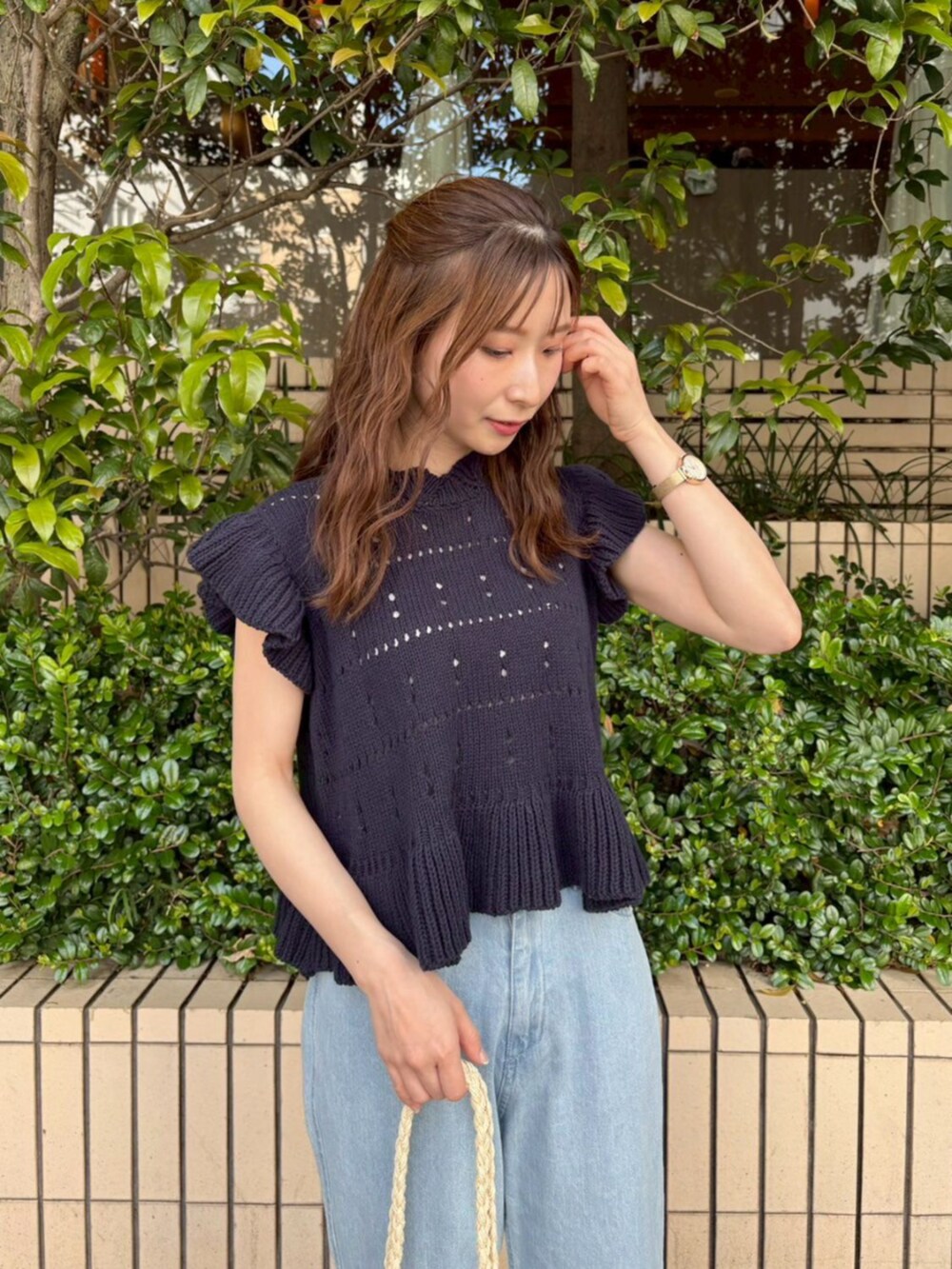 ベージュ系のかごバッグ、ブルー系のデニムパンツ、ブルー系のニット/セーターを着用したレディースの春コーディネートの3枚目の写真