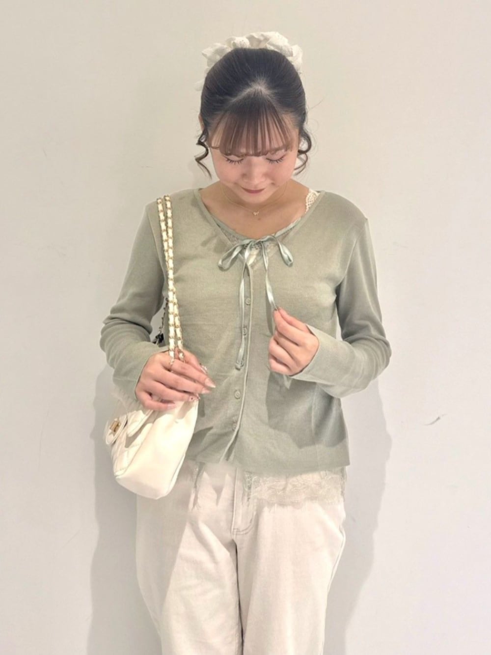 ホワイト系のショルダーバッグ、ホワイト系のデニムパンツ、グリーン系のカーディガン/ボレロを着用したレディースの夏コーディネートの2枚目の写真