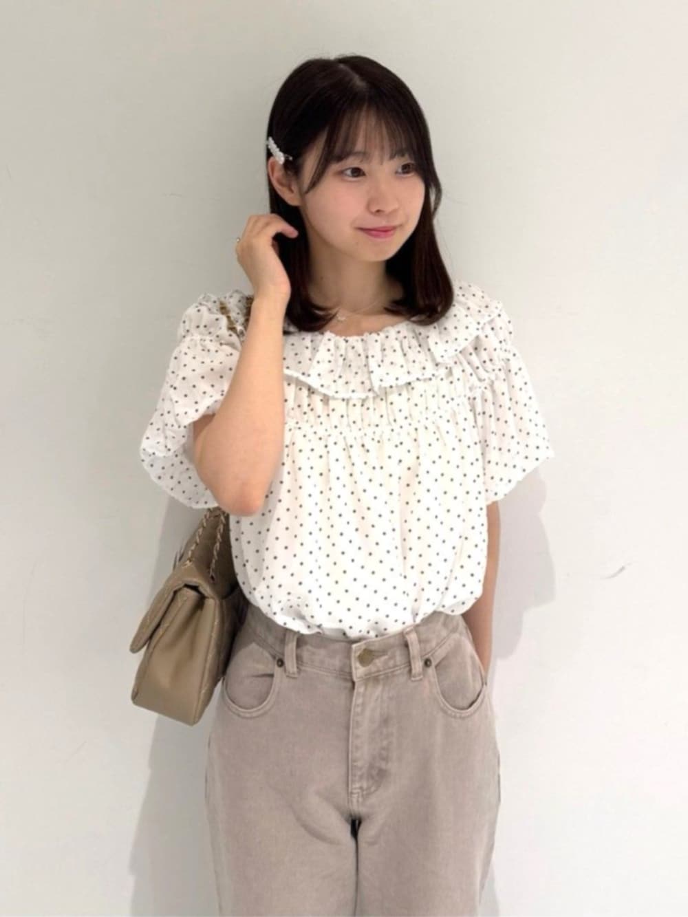 ベージュ系のショルダーバッグ、ホワイト系のシャツ/ブラウス、ピンク系のデニムパンツを着用したレディースの夏コーディネートの2枚目の写真