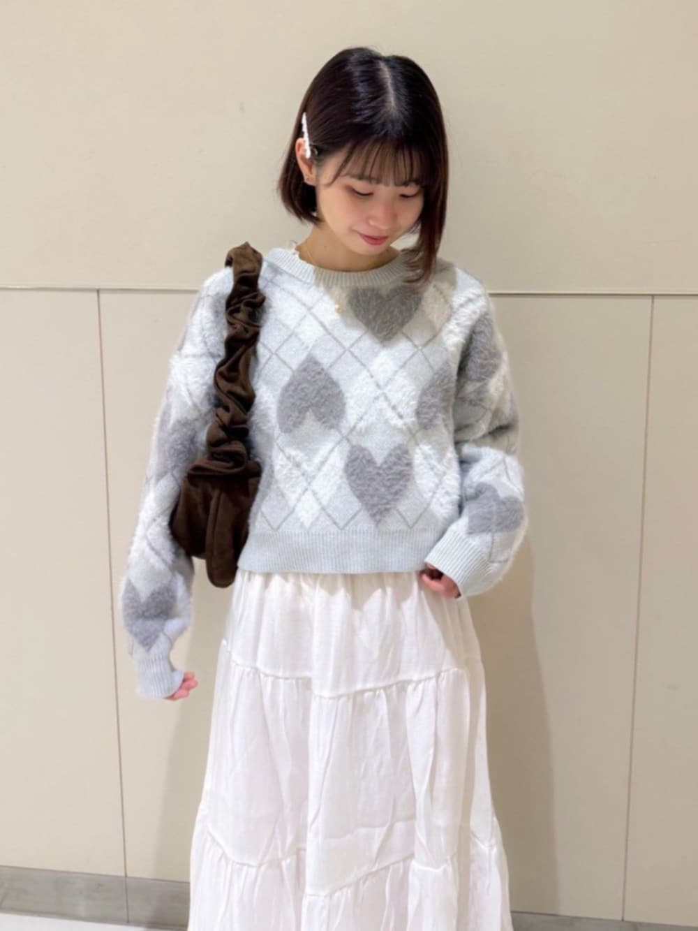 ブラウン系のショルダーバッグ、ホワイト系のスカート、グレー系のニット/セーターを着用したレディースの秋コーディネートの2枚目の写真