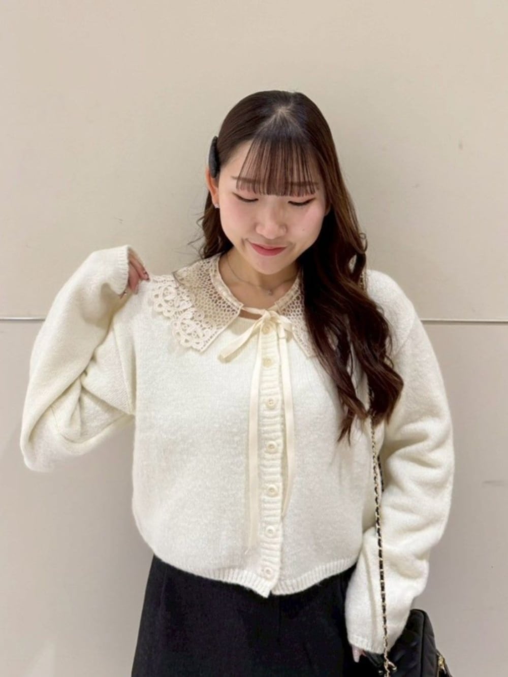 ブラック系のショルダーバッグ、イエロー系のカーディガン/ボレロ、グレー系のスカートを着用したレディースの冬コーディネートの2枚目の写真