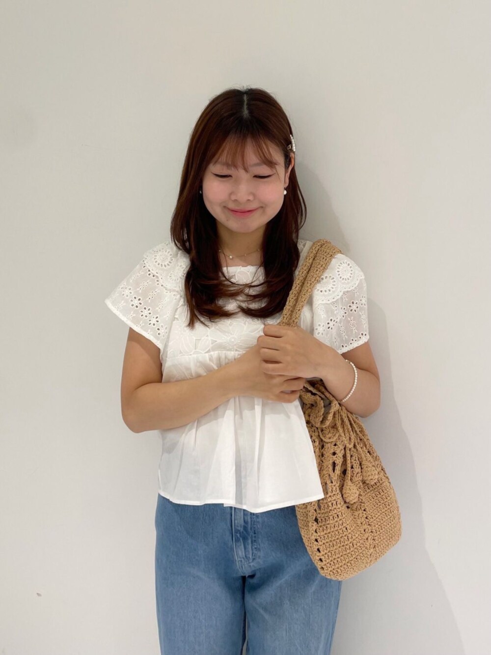 ブルー系のデニムパンツ、ホワイト系のシャツ/ブラウス、ブラウン系のショルダーバッグを着用したレディースの夏コーディネートの2枚目の写真