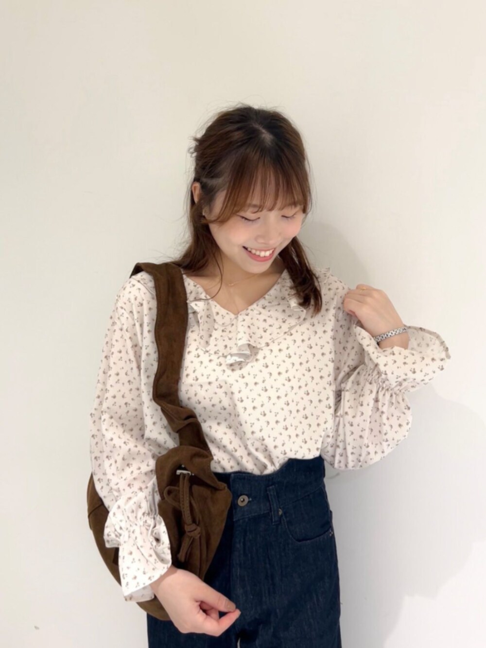 ブラウン系のショルダーバッグ、ブルー系のデニムパンツ、ホワイト系のシャツ/ブラウスを着用したレディースの秋コーディネートの2枚目の写真