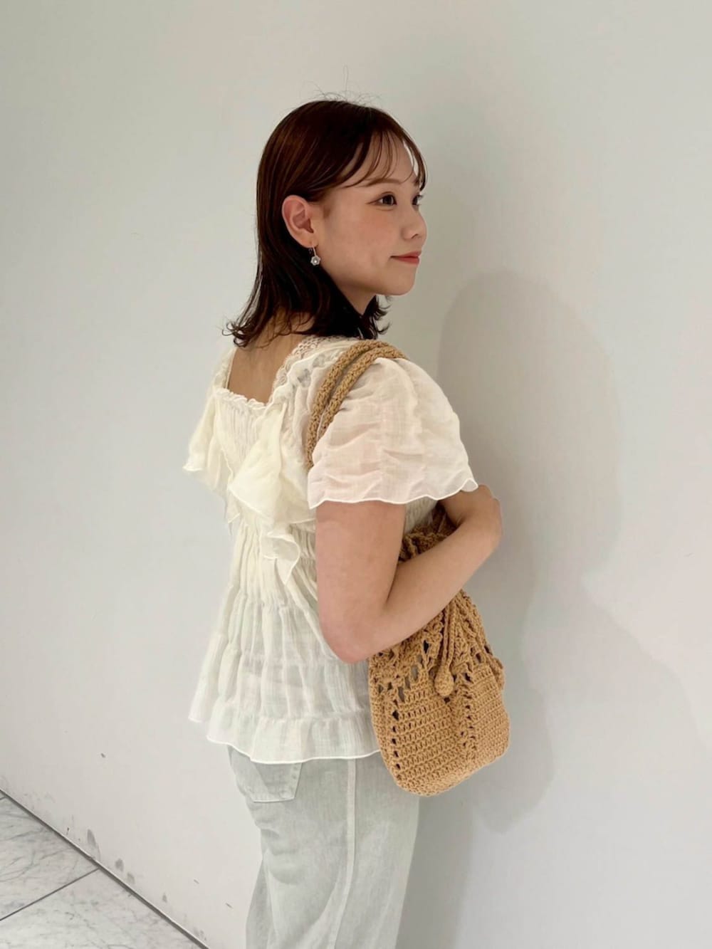 ホワイト系のシャツ/ブラウス、ブラウン系のショルダーバッグ、グリーン系のデニムパンツを着用したレディースの夏コーディネートの3枚目の写真