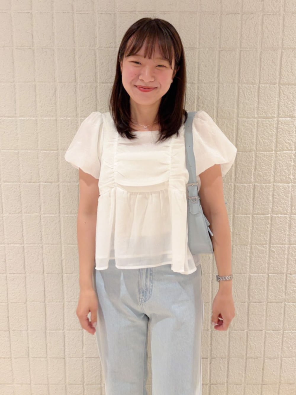 ブルー系のデニムパンツ、ブルー系のショルダーバッグ、ホワイト系のシャツ/ブラウスを着用したレディースの春コーディネートの2枚目の写真