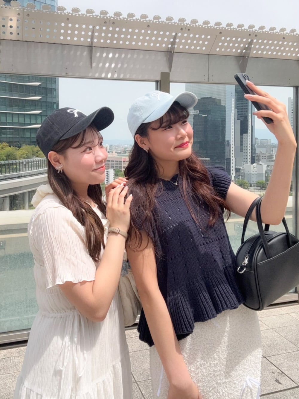 ブラック系のハンドバッグ、ブルー系のニット/セーター、ホワイト系のスカートを着用したレディースの春コーディネートの3枚目の写真