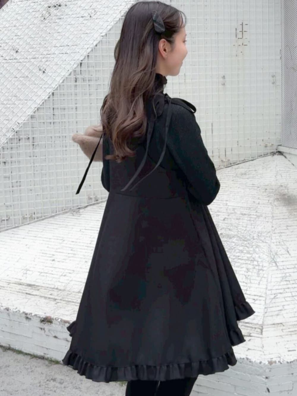 ブラウン系のノーカラーコート、ブラック系のワンピース、ブラック系のニット/セーターを着用したレディースの冬コーディネートの3枚目の写真