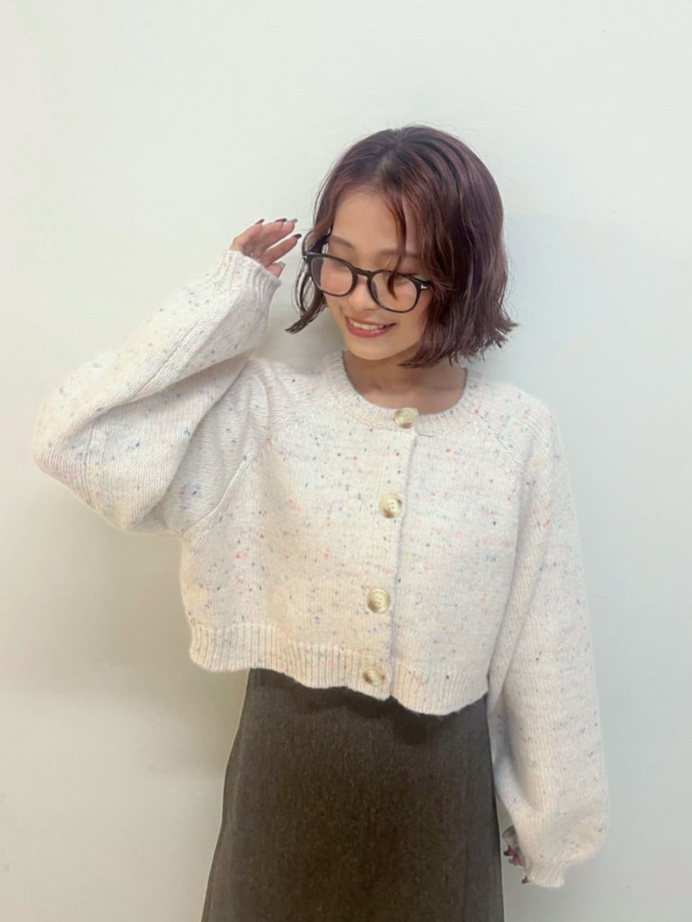 ブラウン系のスカート、ホワイト系のカーディガン/ボレロ、ブラウン系のブーツを着用したレディースの秋コーディネートの2枚目の写真