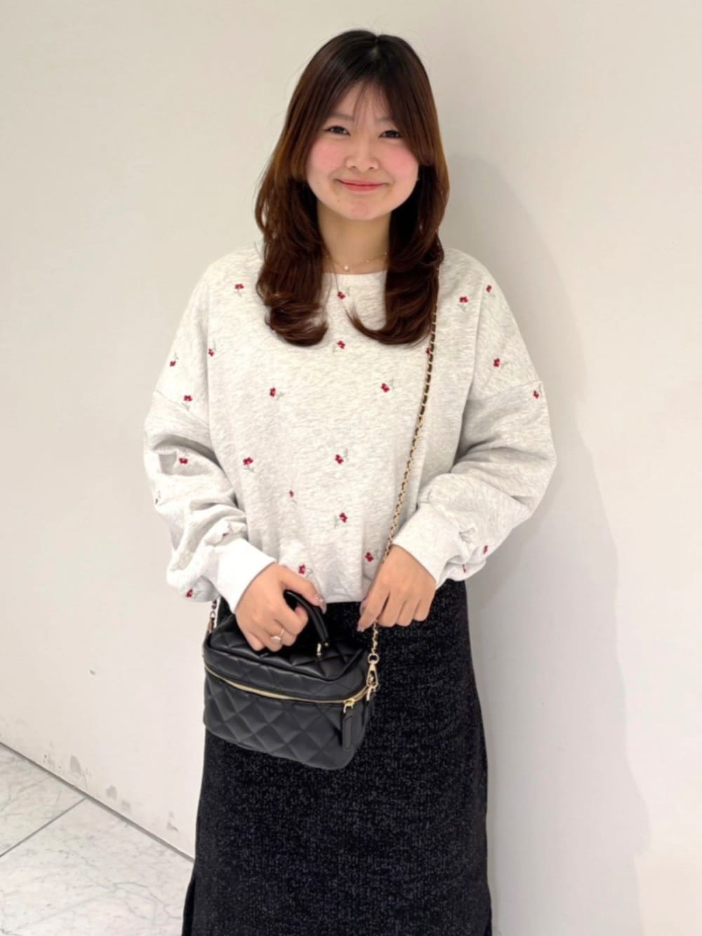 ブラック系のスカート、ブラック系のショルダーバッグ、ホワイト系のスウェットを着用したレディースの冬コーディネートの2枚目の写真