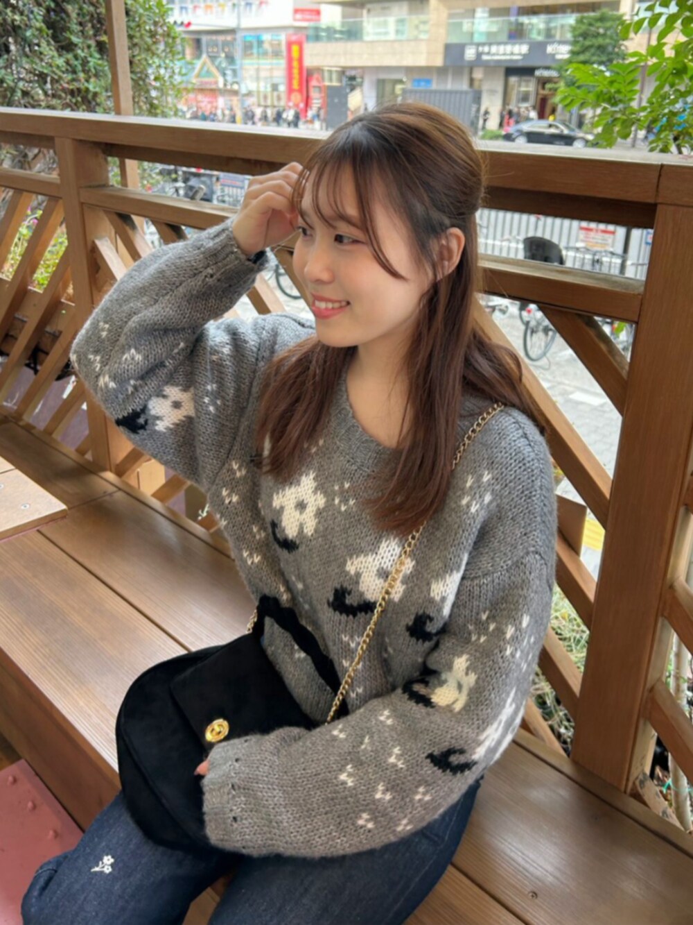 ブラック系のショルダーバッグ、ホワイト系のノーカラーコート、ブルー系のデニムパンツを着用したレディースの冬コーディネートの3枚目の写真