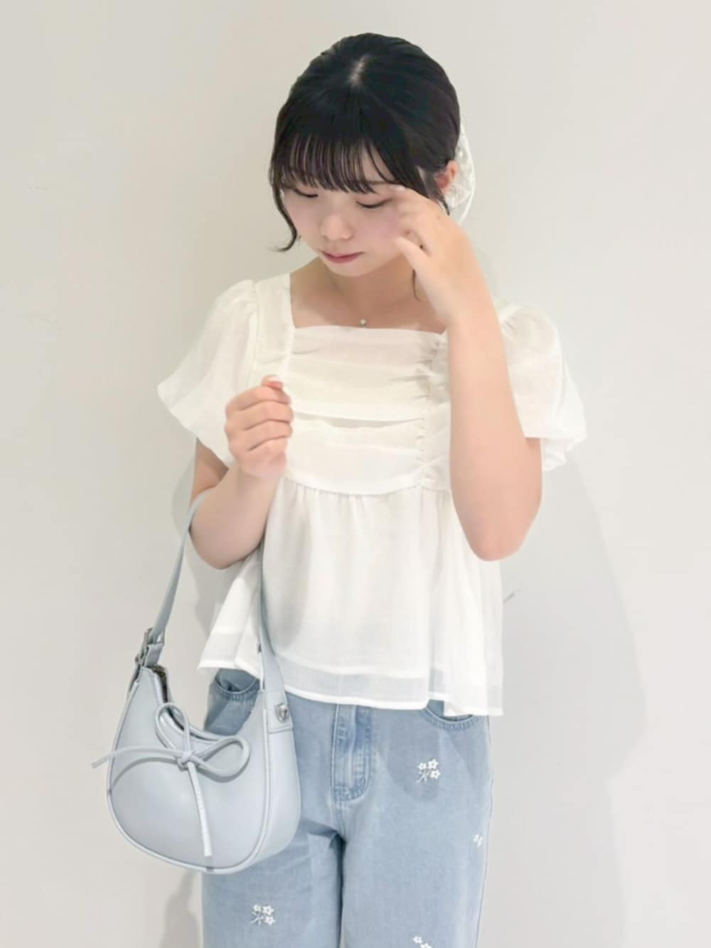 ブルー系のデニムパンツ、ブルー系のショルダーバッグ、ホワイト系のシャツ/ブラウスを着用したレディースの春コーディネートの2枚目の写真