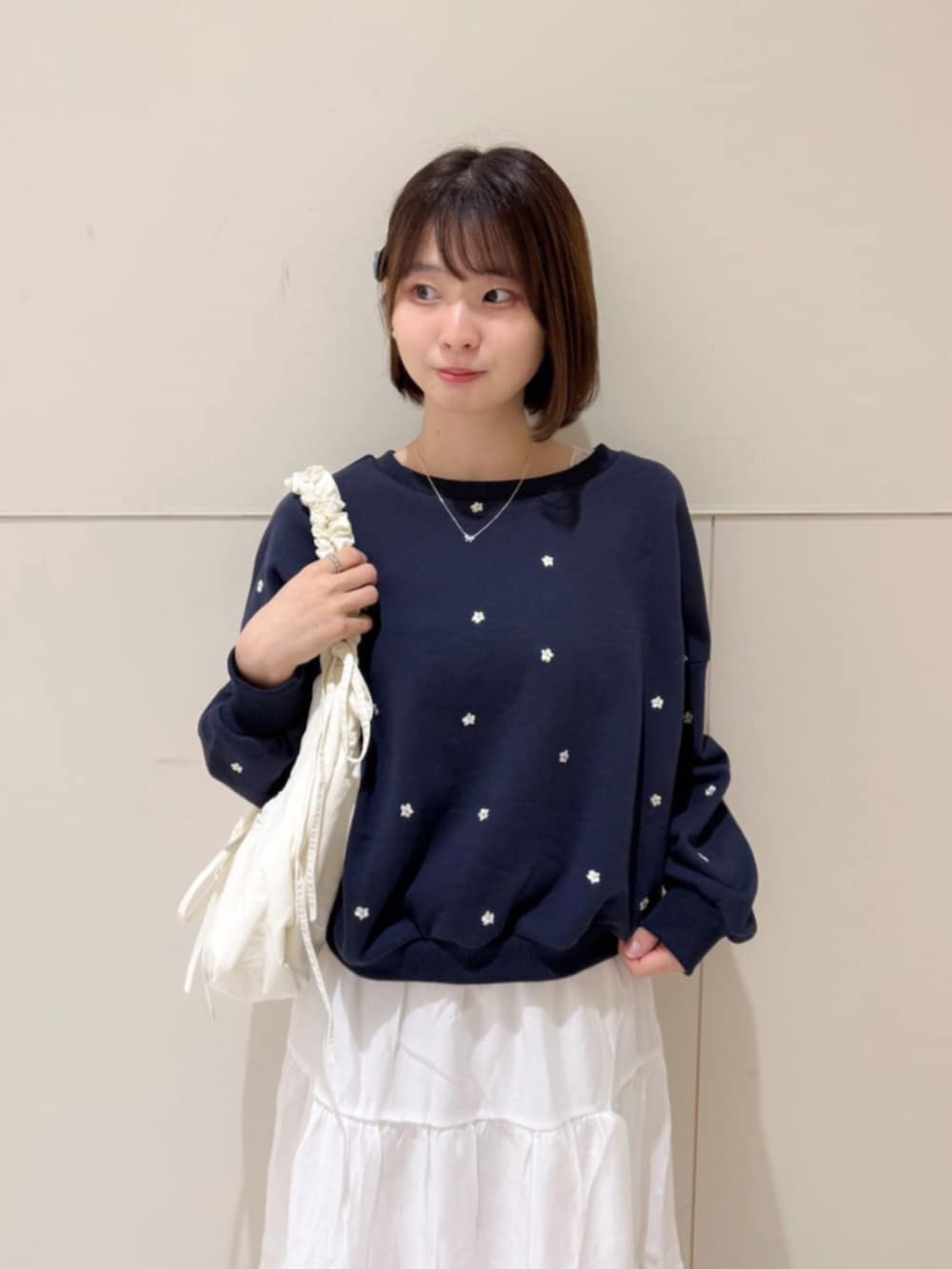 ホワイト系のショルダーバッグ、ホワイト系のスカート、ブルー系のスウェットを着用したレディースの秋コーディネートの2枚目の写真