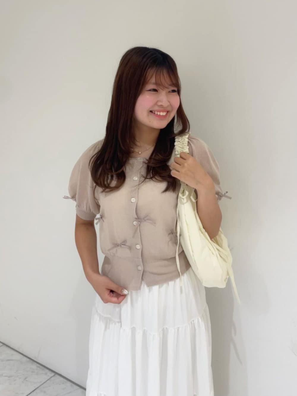 ホワイト系のショルダーバッグ、ホワイト系のスカート、ピンク系のカーディガン/ボレロを着用したレディースの夏コーディネートの2枚目の写真