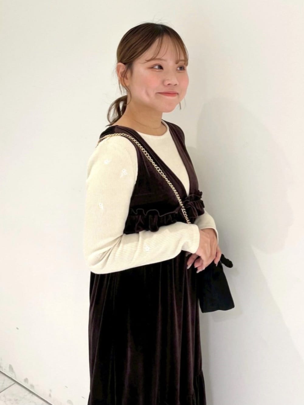 ブラック系のショルダーバッグ、ブラウン系のワンピース、ホワイト系のTシャツ/カットソーを着用したレディースの冬コーディネートの2枚目の写真