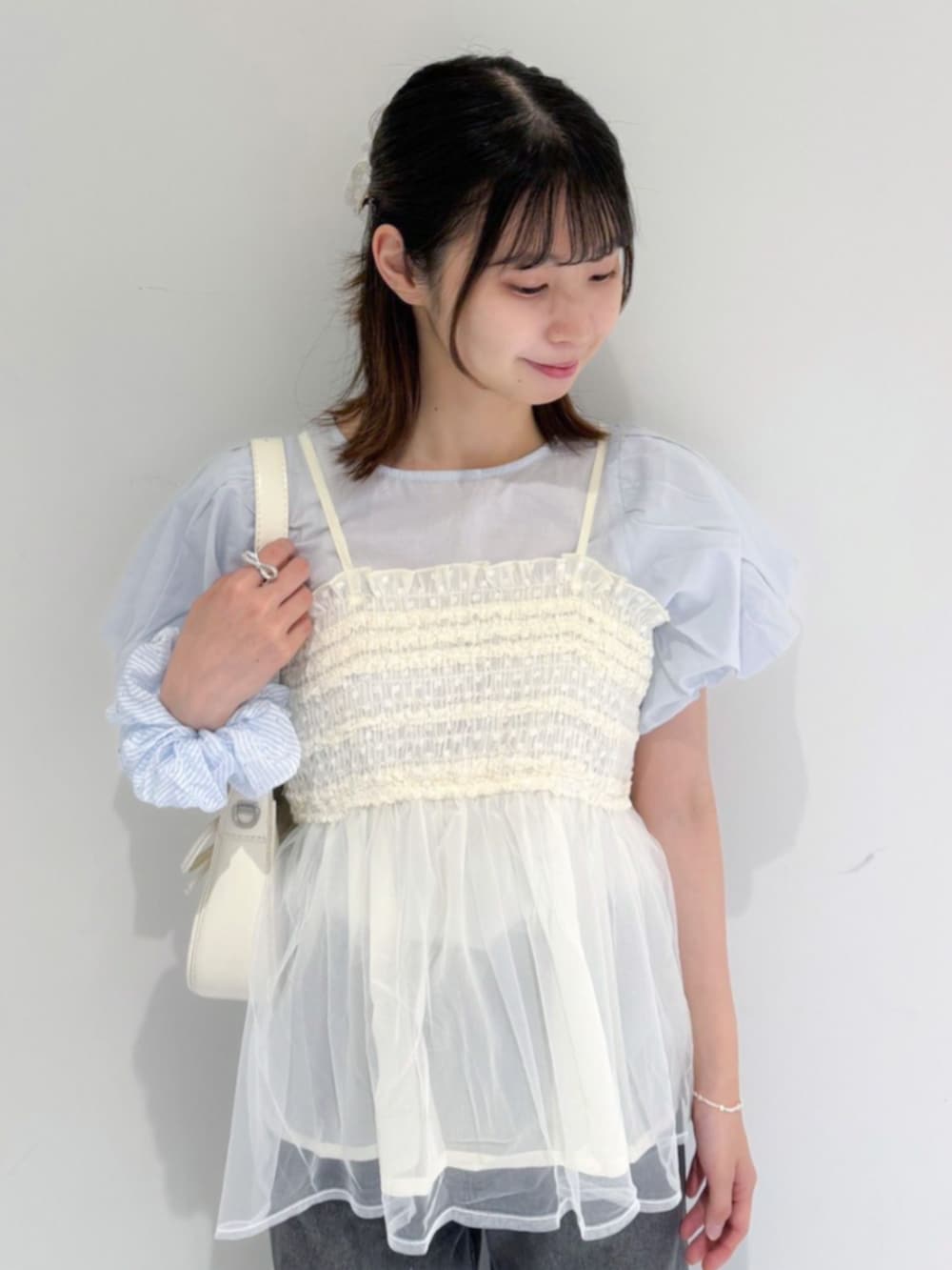 ブラック系のデニムパンツ、ブルー系のシャツ/ブラウス、ホワイト系のショルダーバッグを着用したレディースの夏コーディネートの2枚目の写真