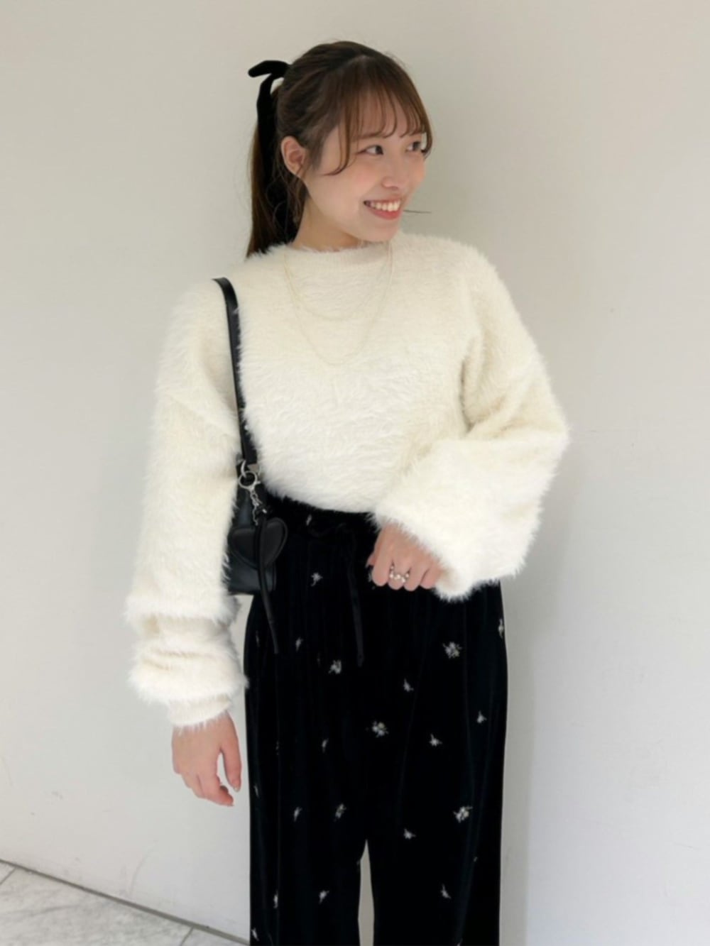 ブラック系のその他パンツ、ホワイト系のニット/セーター、ブラック系のショルダーバッグを着用したレディースの冬コーディネートの2枚目の写真