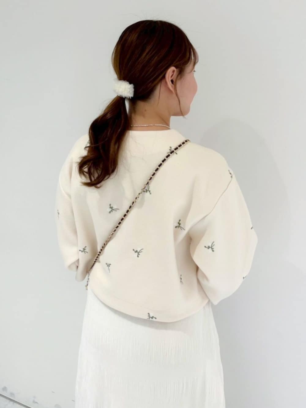 ブラウン系のショルダーバッグ、ホワイト系のスカート、ホワイト系のノーカラージャケットを着用したレディースの冬コーディネートの3枚目の写真