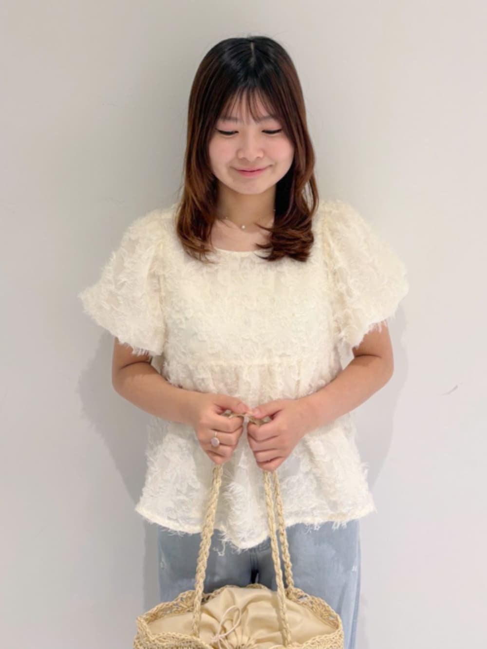 ホワイト系のかごバッグ、ブルー系のデニムパンツ、ホワイト系のシャツ/ブラウスを着用したレディースの夏コーディネートの2枚目の写真