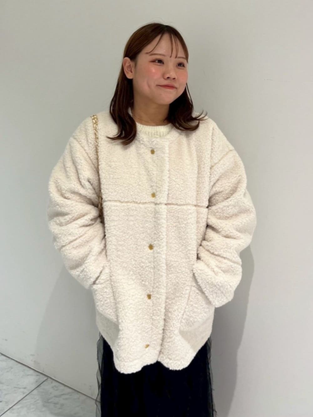 ホワイト系のショルダーバッグ、ブラック系のスカート、ホワイト系のムートンコートを着用したレディースの秋コーディネートの2枚目の写真