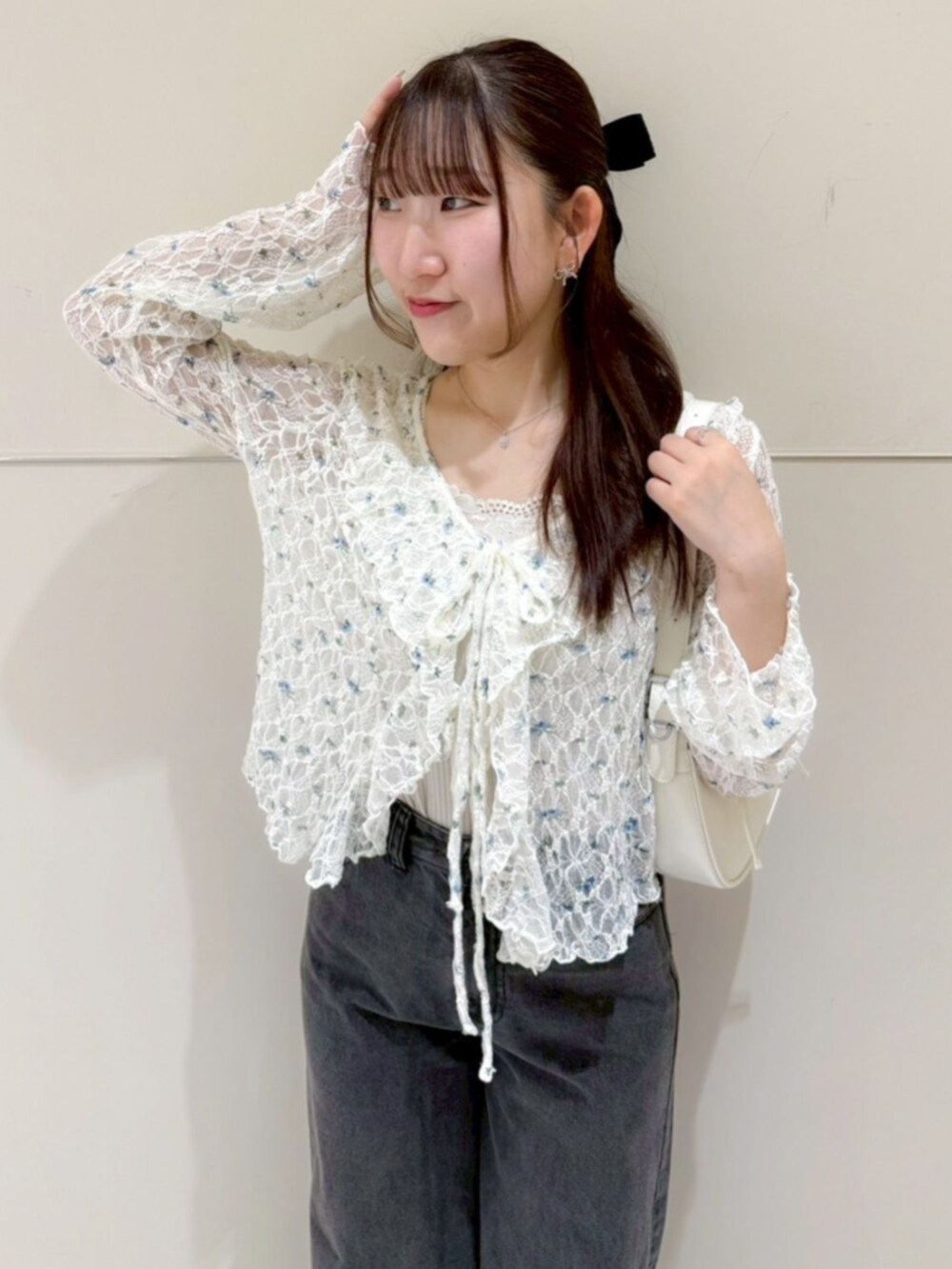 ブラック系のデニムパンツ、ホワイト系のショルダーバッグ、ブルー系のカーディガン/ボレロを着用したレディースの春コーディネートの2枚目の写真