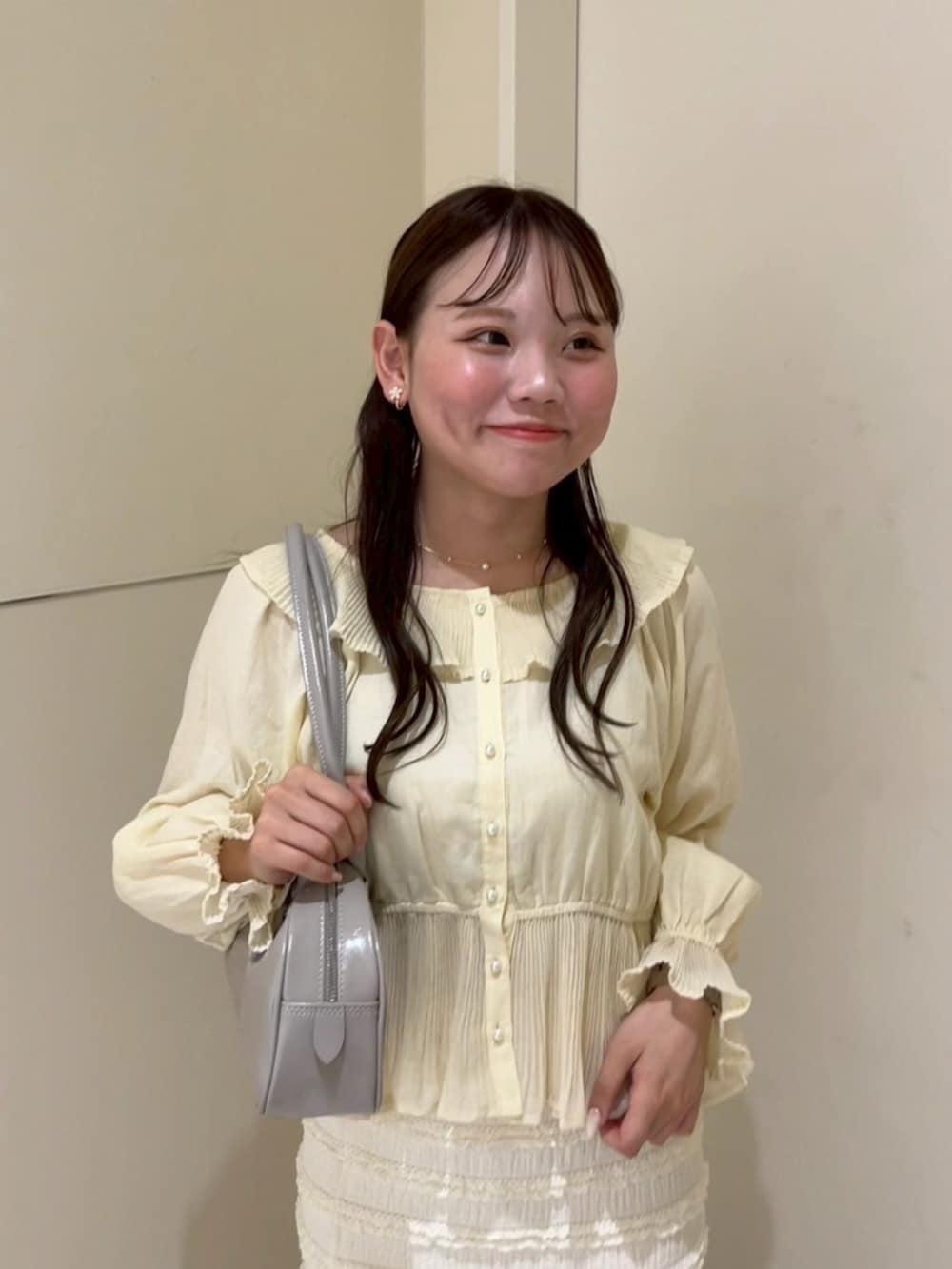 イエロー系のシャツ/ブラウス、ホワイト系のスカート、グレー系のショルダーバッグを着用したレディースの春コーディネートの2枚目の写真
