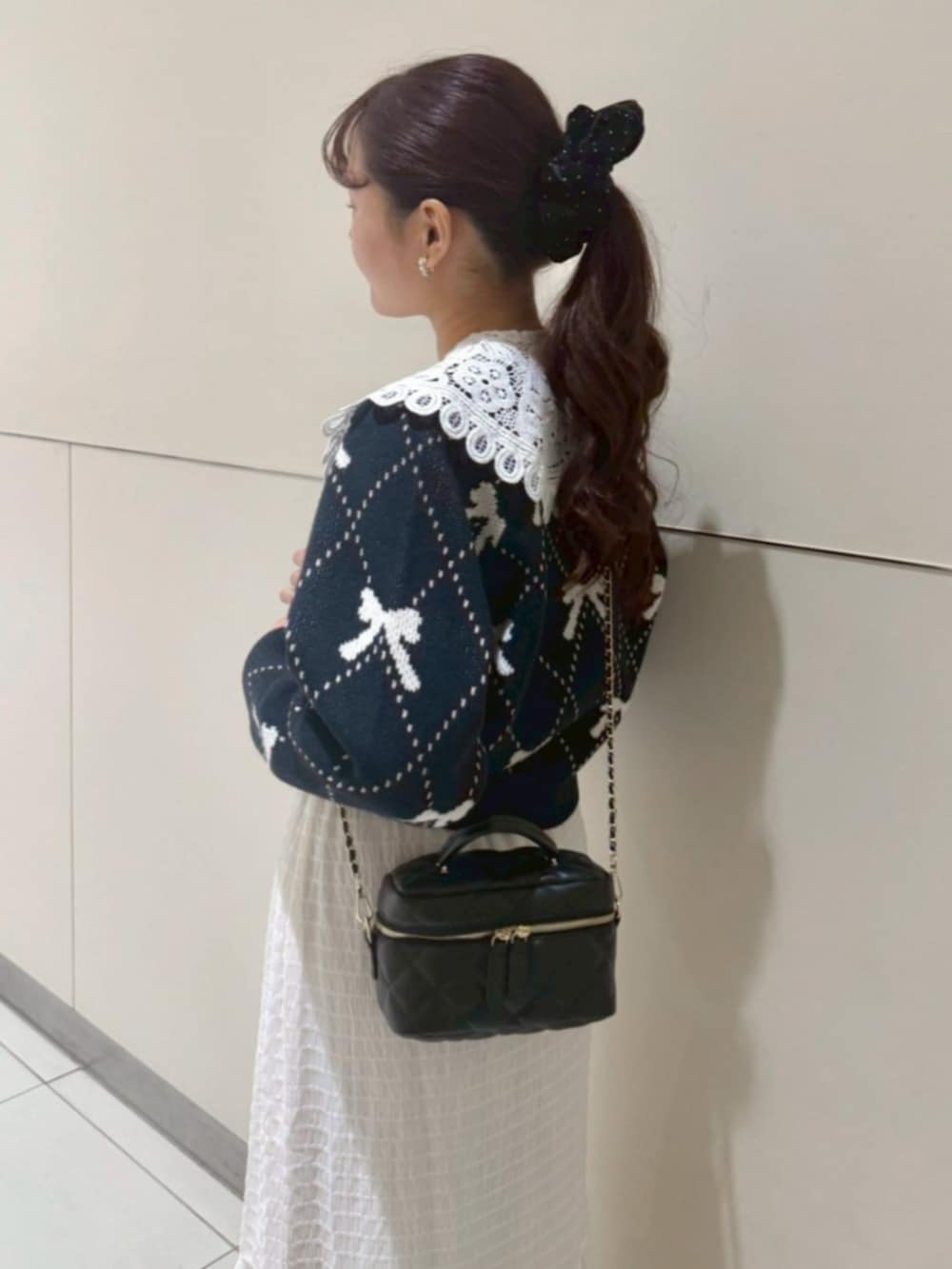 ホワイト系のスカート、ブラック系のショルダーバッグ、ブルー系のニット/セーターを着用したレディースの秋コーディネートの3枚目の写真