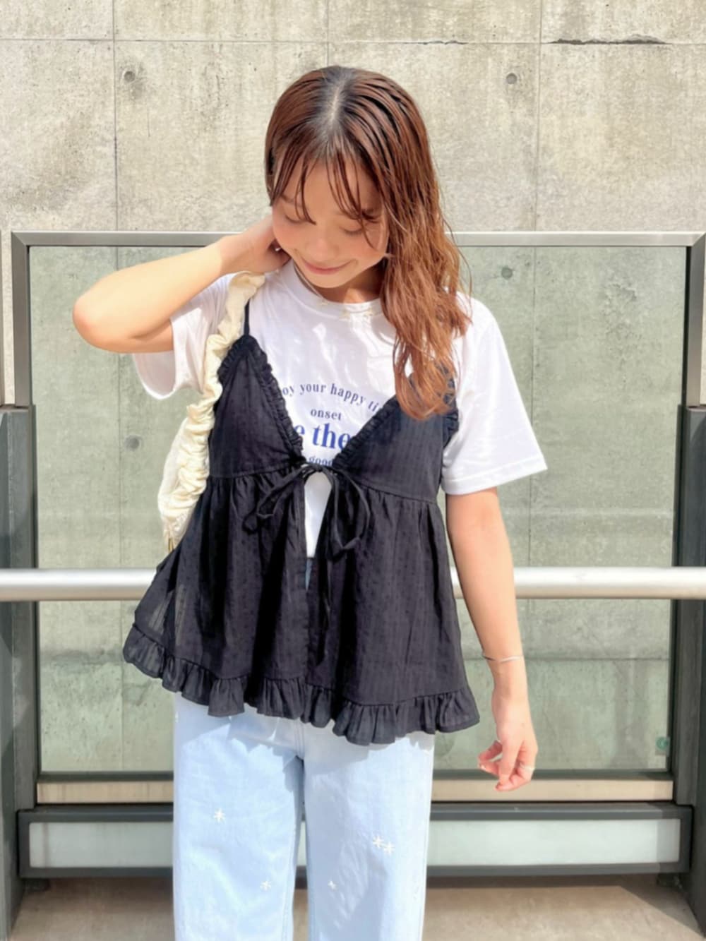 ホワイト系のショルダーバッグ、ブルー系のデニムパンツ、ブラック系のキャミソールを着用したレディースの夏コーディネートの2枚目の写真