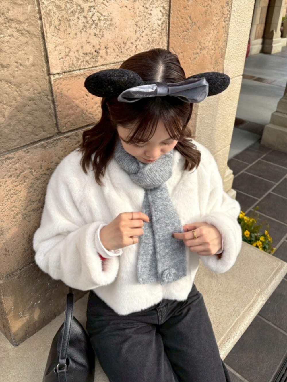 ブラック系のデニムパンツ、ホワイト系のノーカラーコート、グレー系のマフラーを着用したレディースの冬コーディネートの2枚目の写真